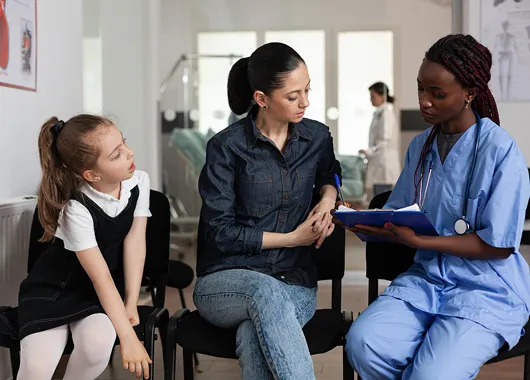 A medical professional discussing forms with a mother and child.
